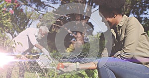 Spot of light against african american father and daughter gardening together in the garden