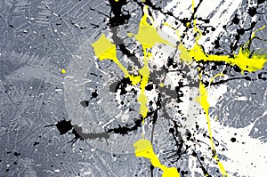 A spot of white and black and yellow spilled paint on a concrete textured surface