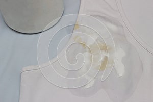 Spot on a white T-shirt filled with stain remover, fighting stains on clothes, white T-shirt, close-up, container stain remover