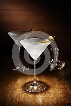 Spotlight on 2 Chilled martinis, with olives, shot on a dark woo