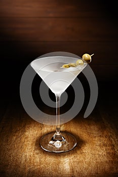 Spotlight on a single chilled martini, with olives, shot on a da