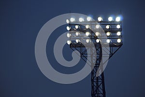 Spotlights illuminate football field while match. Lighting equipment for stadium