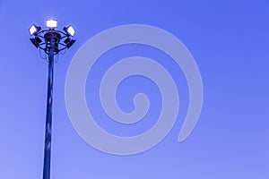 Spotlights tower high voltage in sport stadium on blue sky background