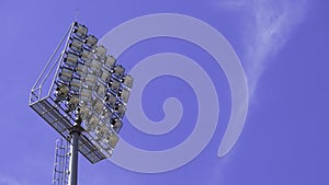 Spotlights tower with a metal pole for the sports arena. Installed around football stadium. Blue sky background