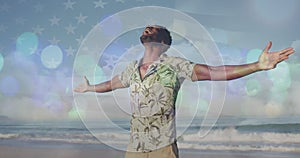 Spots of light against african american man with arms wide open enjoying on the beach