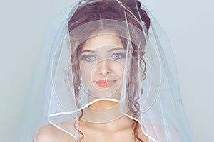 Spouse. Close up shot of elegant, brunette girl, woman, bride posing under veil closeup  light blue background with copy