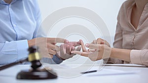 Spouses arguing about property division during divorce, gavel and rings closeup