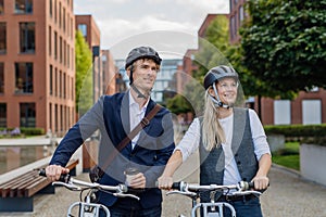 Spouses commuting through the city, talking and walking by bike on street. Middle-aged city commuters traveling from