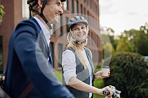 Spouses commuting through the city, talking and walking by bike on street. Middle-aged city commuters traveling from