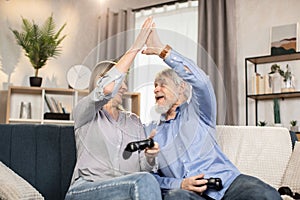 Spouses giving high five after winning computer game at home