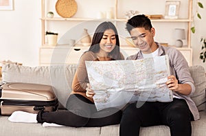 Spouses Holding World Map Planning Travel Sitting On Sofa Indoors