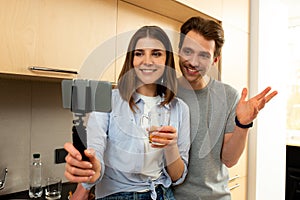 Spouses making selfie by smartphone on tripod at home