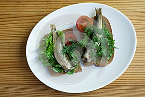 Sprats, bread and tomatoes on a saucer