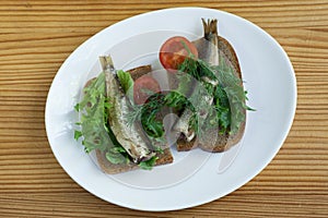 Sprats, bread and tomatoes on a saucer