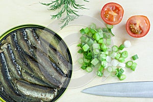 Sprats, onion and tomatoes on a cutting board