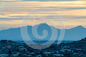 Sprawling mountain wilderness sunset with houses and homes in desert neighborhood with orange skies and blue clouds