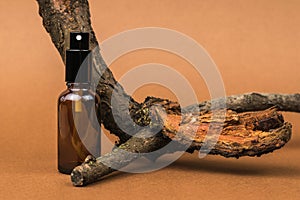 A spray bottle and an old tree on a brown background. Cosmetics and medicinal products based on natural minerals