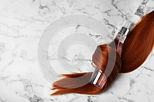 Spray bottle wrapped in lock of hair on white background, flat lay with space for text. Natural cosmetic products