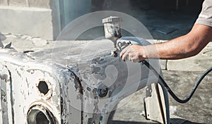 Spray gun in the hand of a painter. Painting car details