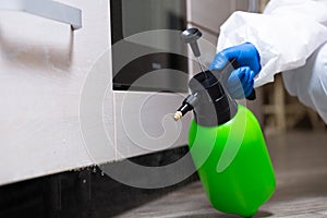 Spray gun with pesticides close-up. An exterminator in work clothes sprays pesticides from a spray bottle. Fight against