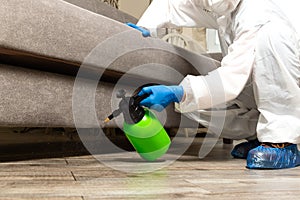 Spray gun with pesticides close-up. An exterminator in work clothes sprays pesticides from a spray bottle. Fight against