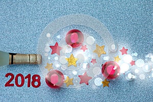 Spray of the stars and Christmas tree balls from a bottle of champagne on silver background. The time of Christmas and New Year`