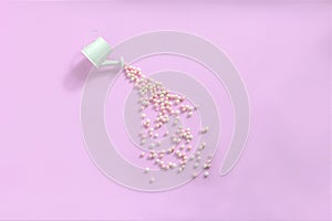 Sprayed watering can with of candy on pink background. Round sweet peas sprinkle. Creative sweet concept. Flat lay, top view, copy