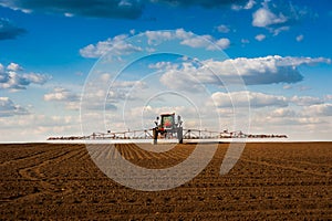 sprayer with long arms, fertilizer spreader that fertilizes farm fields view with beautiful clouds photo