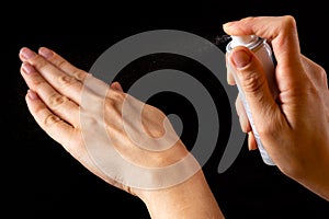 Spraying antiseptics on hands for disinfection on a black background