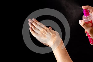 Spraying antiseptics on hands for disinfection on a black background