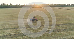 Spraying a field with wheat view from a drone. A tractor sprays wheat with herbicides. The tractor sprays the wheat