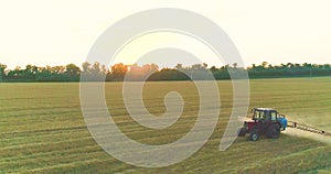 Spraying a field with wheat view from a drone. A tractor sprays wheat with herbicides. The tractor sprays the wheat