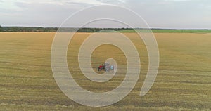 Spraying a field with wheat view from a drone. A tractor sprays wheat with herbicides. The tractor sprays the wheat