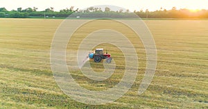 Spraying a field with wheat view from a drone. A tractor sprays wheat with herbicides. The tractor sprays the wheat