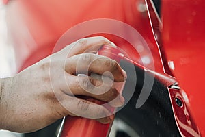 spraying grease on the car door mechanism at shallow depth of field