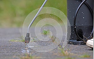 Spraying pesticide with portable sprayer to eradicate garden weeds