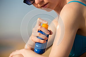 Spraying sunscreen lotion on shoulder photo