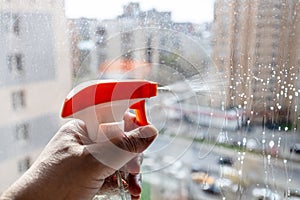 spraying washing liquid on window glass close up