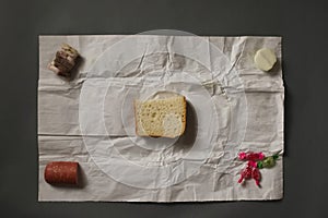 On spread sheet of paper there is bread, onions, sweets, lard an