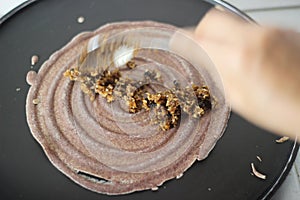 Spreading the finger millet batter on a hot griddle