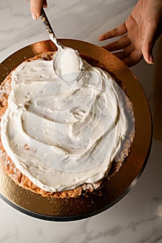 Spreading thick, greasy white cream on cakes, on a cake stand