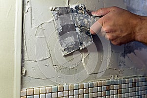 Spreading of tile adhesive with a trowel.