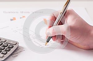 Spreadsheet with hand holding pen and calculator in business stock balance sheet