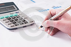 Spreadsheet with hand holding pen and calculator in business stock balance sheet