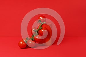 Sprig of Fresh cherry tomatoes on wooden podium on a red background. monochrome