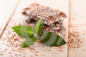 Sprig of mint in front of chocolate stack on white board