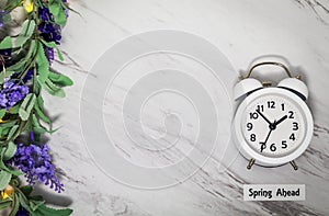 Spring Ahead Daylight Saving Time Concept on gray marble with white clock