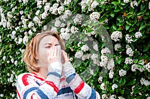 Spring allergy. Woman blowing near spring tree in bloom.