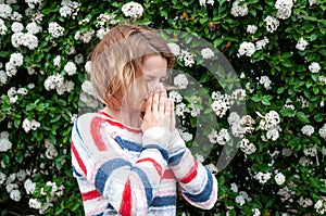 Spring allergy. Woman blowing near spring tree in bloom.