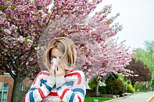 Spring allergy. Woman blowing near spring tree in bloom.